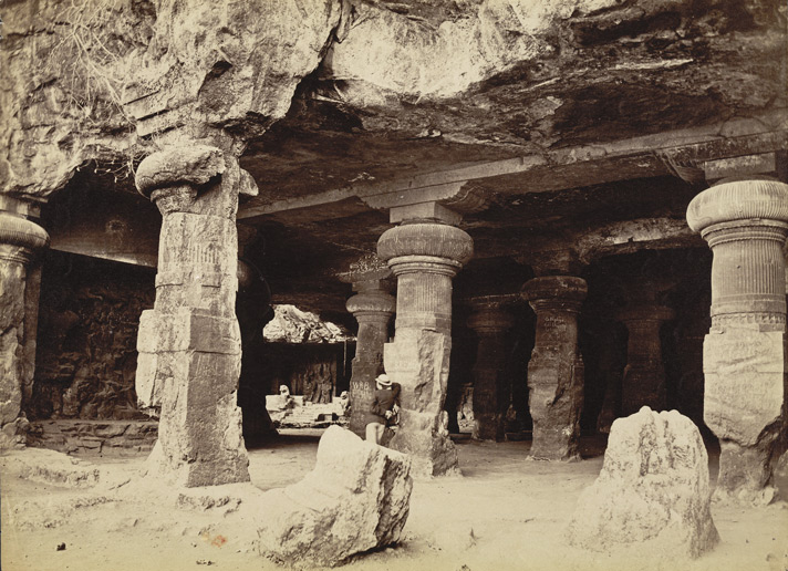 Photograph of Interior Views of the Elephanta Caves (with a visitor in the foreground). Location: Off the coast of Bombay (Mumbai), circa 1875, Bellew Collection of Architectural Views. Image credit: Asia, Pacific, and Africa Collections, British Library.